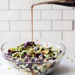 Salad in a bowl with dressing being poured on top.