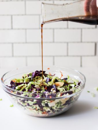 Salad in a bowl with dressing being poured on top.