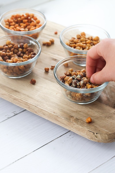 Roasted chickpeas seasoned 4 ways is a great snack under 100 calories a serving and provides about 4 grams of fiber and protein in a serving! They are easy to prepare and can be used in soups, salads, pasta or rice dishes or eaten straight from the oven. | mealswithmaggie.com #5ingredientsorless #roastedchickpeas #crunchy #easymealprep #easysnackidea #lowcaloriesnack #highproteinsnack #highfibersnack
