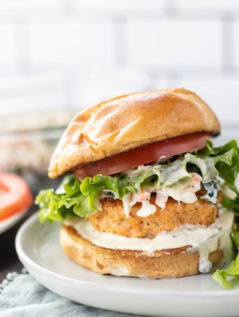 a salmon burger with a bun and lettuce on a plate.