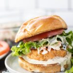 a salmon burger on a bun with lettuce and aioli