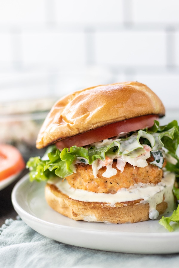 a salmon burger with lettuce and aioli on a plate.