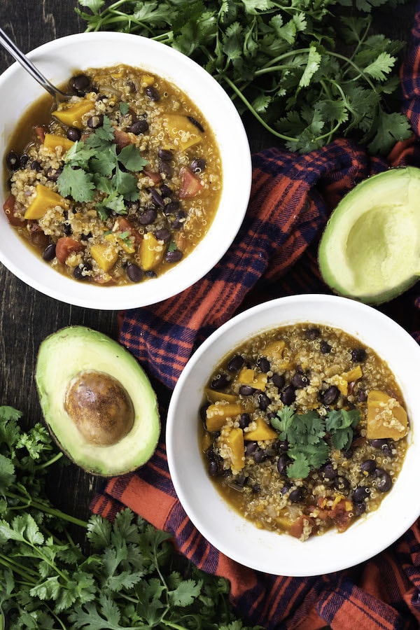 Chili in bowls with an avocado next to it. 