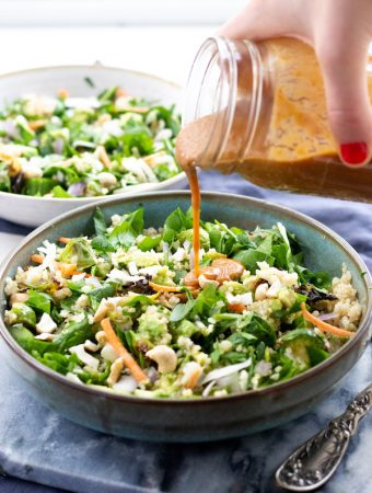 a salad in a bowl with peanut dressing poured over top.