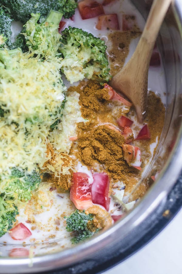 curry and spices in bowl with wooden spoon and raw vegetables. 