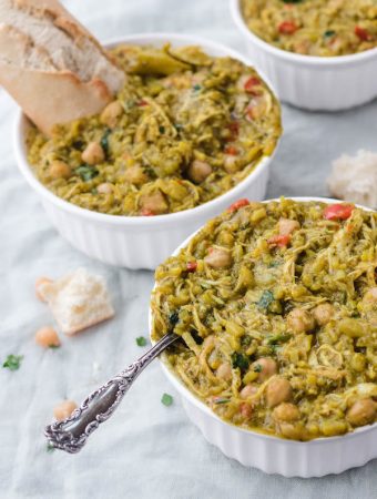 bowls of curry next to each other with bread and spoons coming out of them.