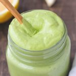 green dressing in a jar with a wooden spoon.
