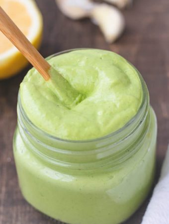 green dressing in a jar with a wooden spoon.