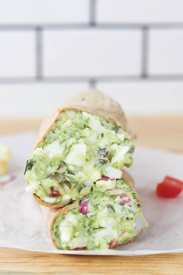 Avocado egg salad in a wrap on a plate in a kitchen.