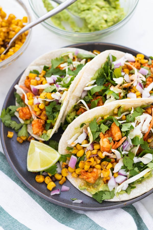 tacos on a plate with corn and red onion.