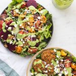 two salads in bowls with green goddess dressing drizzle