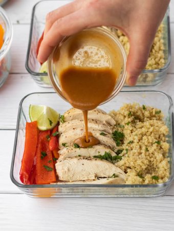 thai peanut sauce being poured on thia chicken meal prep bowl