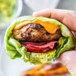 A hand holding a turkey burger in a lettuce wrap.