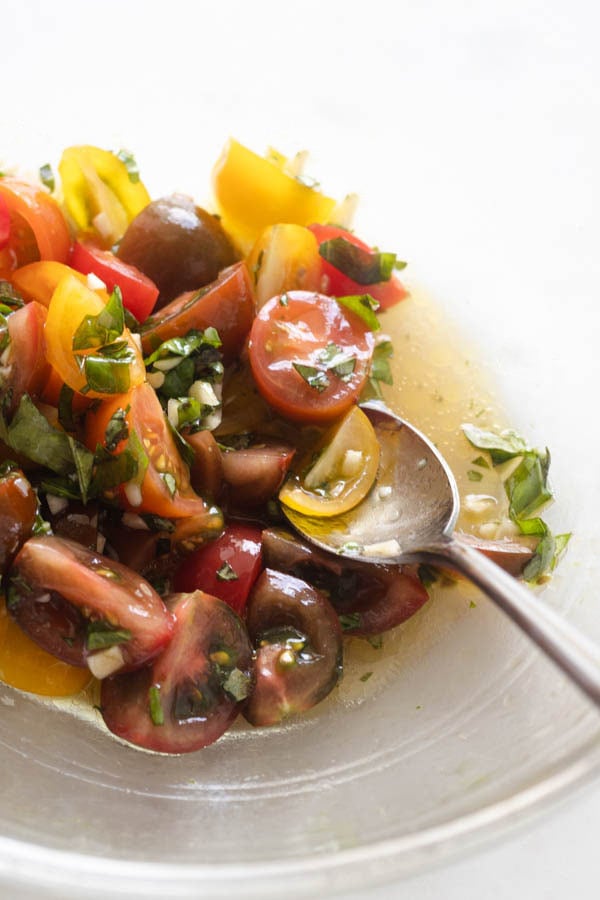 tomatoes in a bowl with a spoon and oil