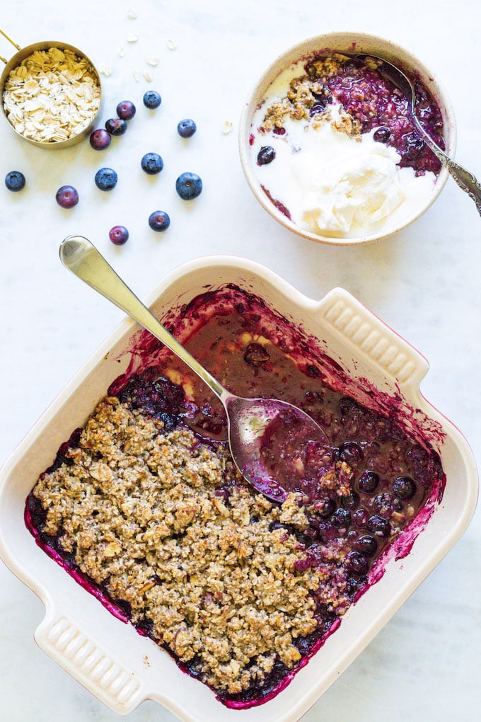 Blueberry crisp from the oven with blueberries around it.