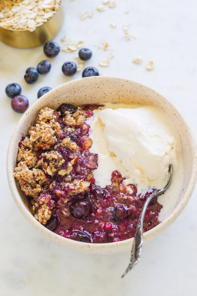 Blueberry crisp with ice cream and a spoon.