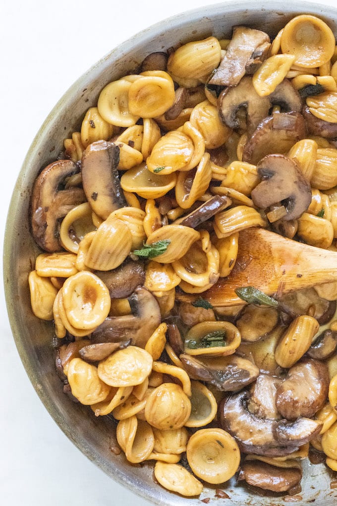 Pasta in a pan with mushrooms and sage.