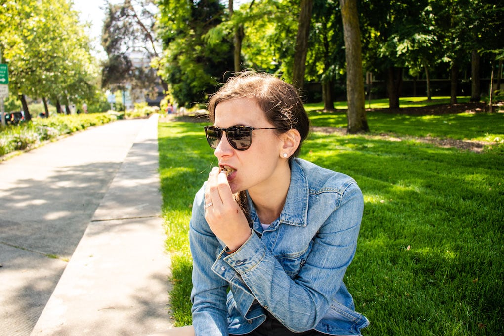 Me eating a cookie sitting on grass.