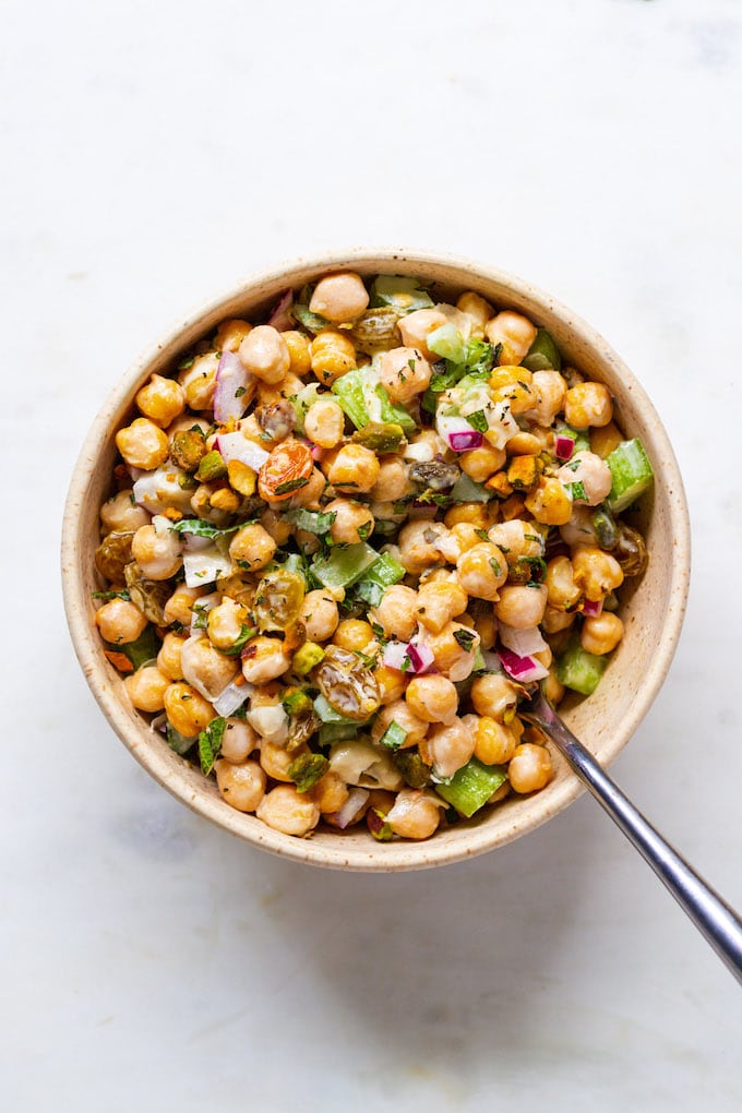 Salad in a bowl with pistachios and mint on top with a fork.