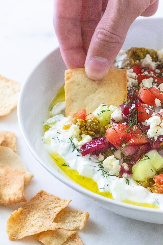 A chip being dipped in a bowl of dip.