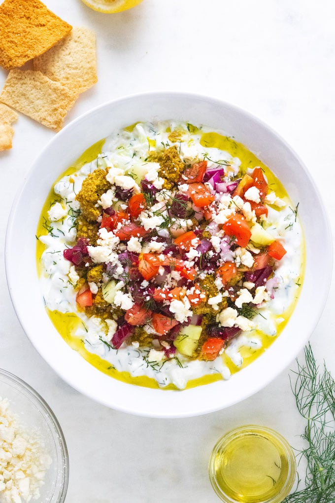 Mediterranean yogurt cucumber dip in a bowl with olive oil drizzled on top.