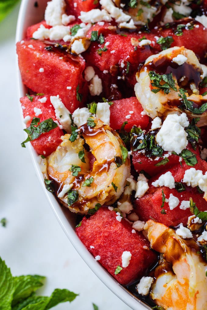 Close up shot of shrimp with mint and feta on it. 