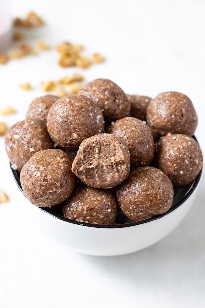 Chocolate protein balls in a bowl with a bite mark.