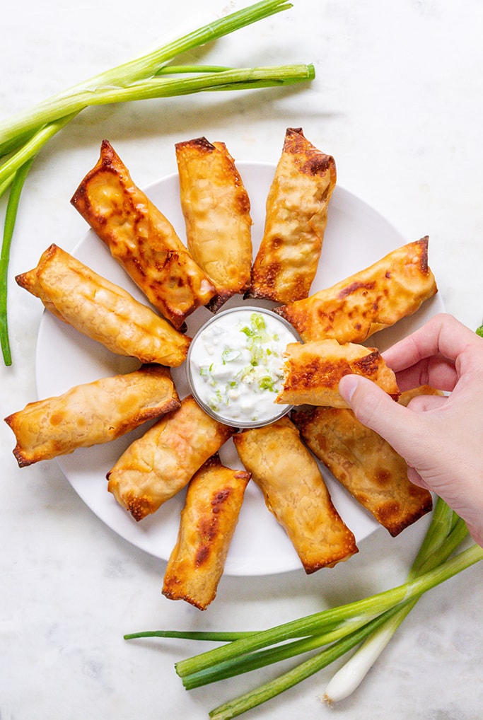 A hand dunking buffalo chicken into dip