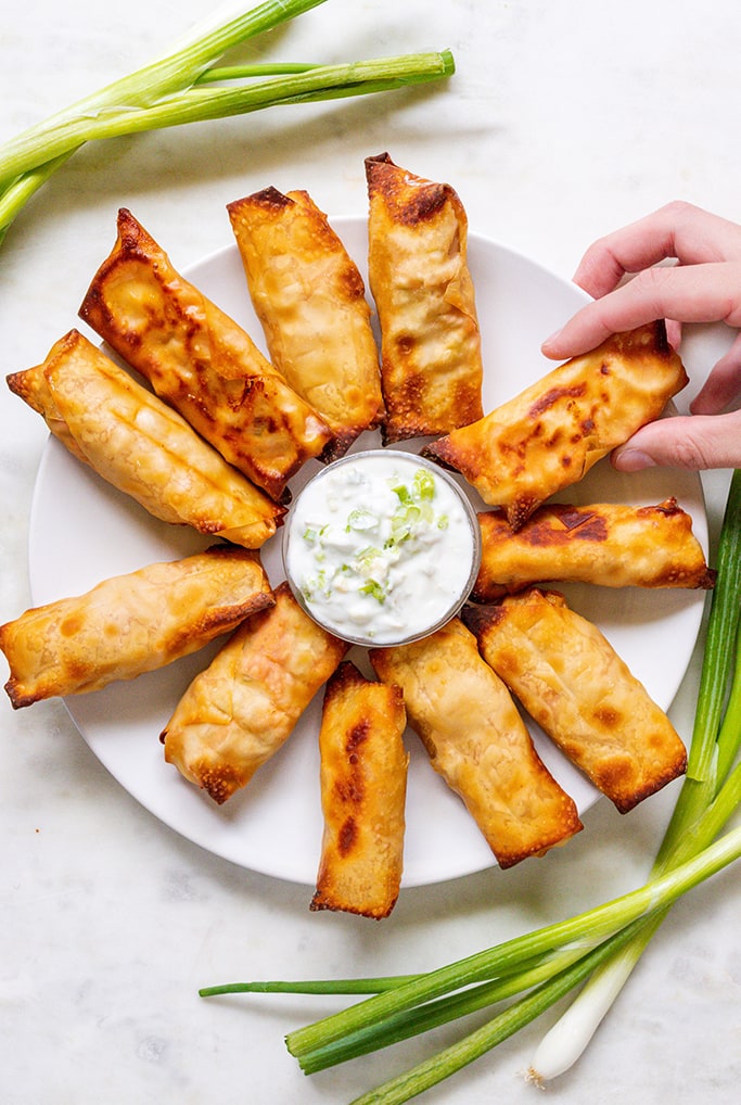 A plate of buffalo chicken wontons with yogurt blue cheese dip in the middle.