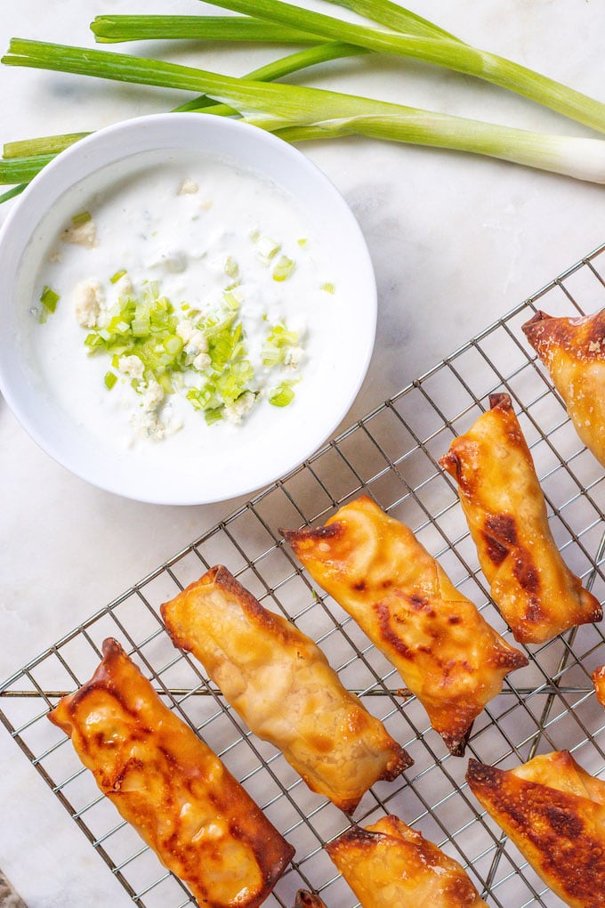 Buffalo chicken wontons and blue cheese dip next to each other.