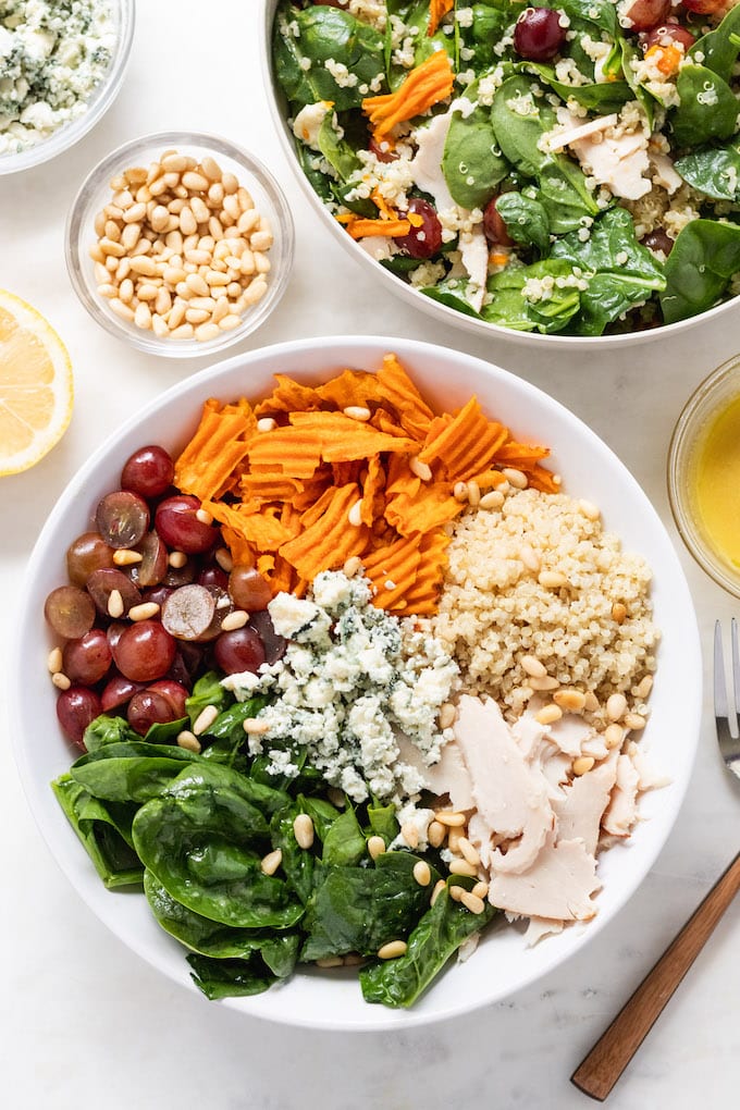 Turkey salad in a bowl with fork next to it and toppings in the bowl.