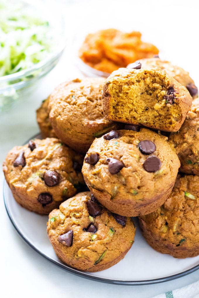 A plate with chocolate chip muffins and one with a bite out of it.