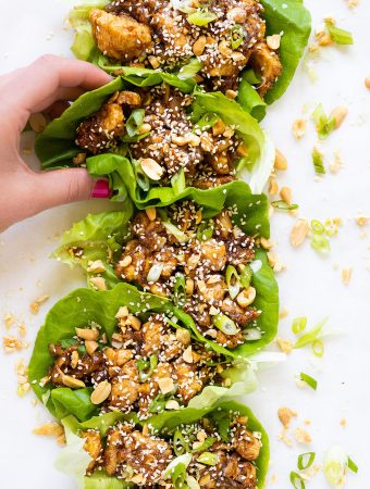 Hand grabbing a lettuce cup full of sesame ginger chicken