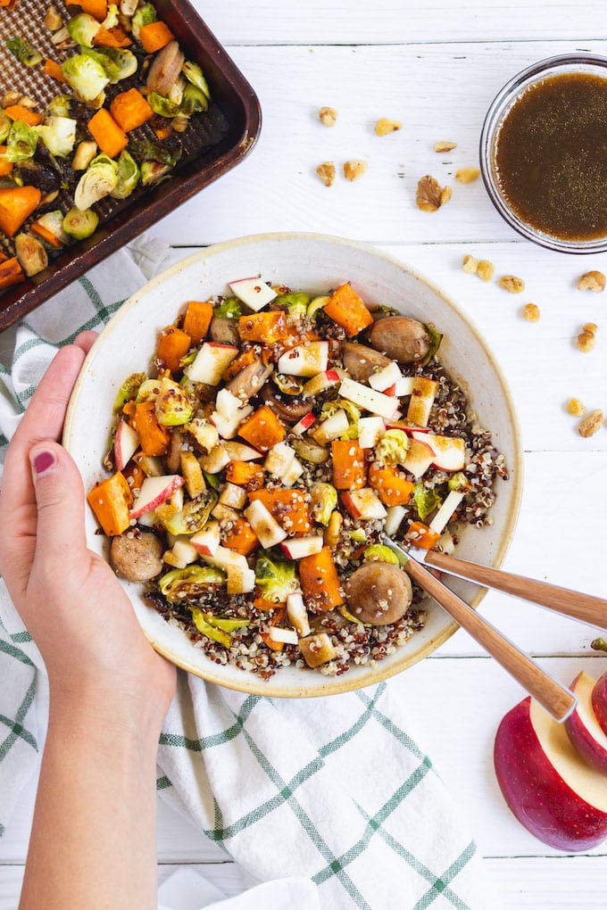 A harvest grain bowl with food in it and a hand around it.