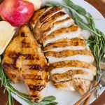 Apple cider chicken on plate with fresh herbs.