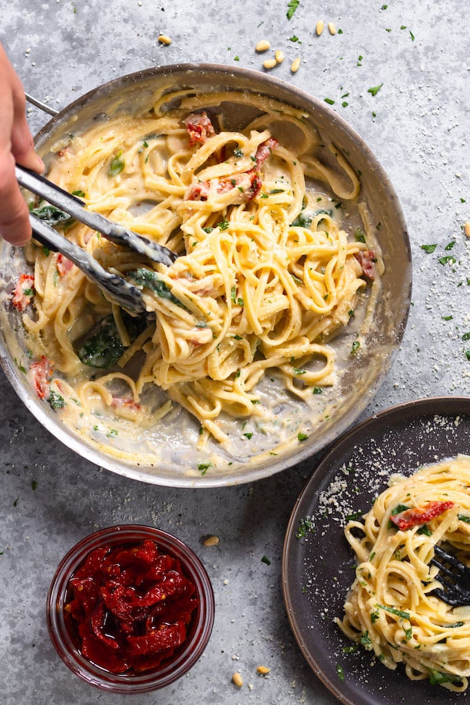 a pan of healthy chicken Alfredo pasta with sun dried tomatoes. 