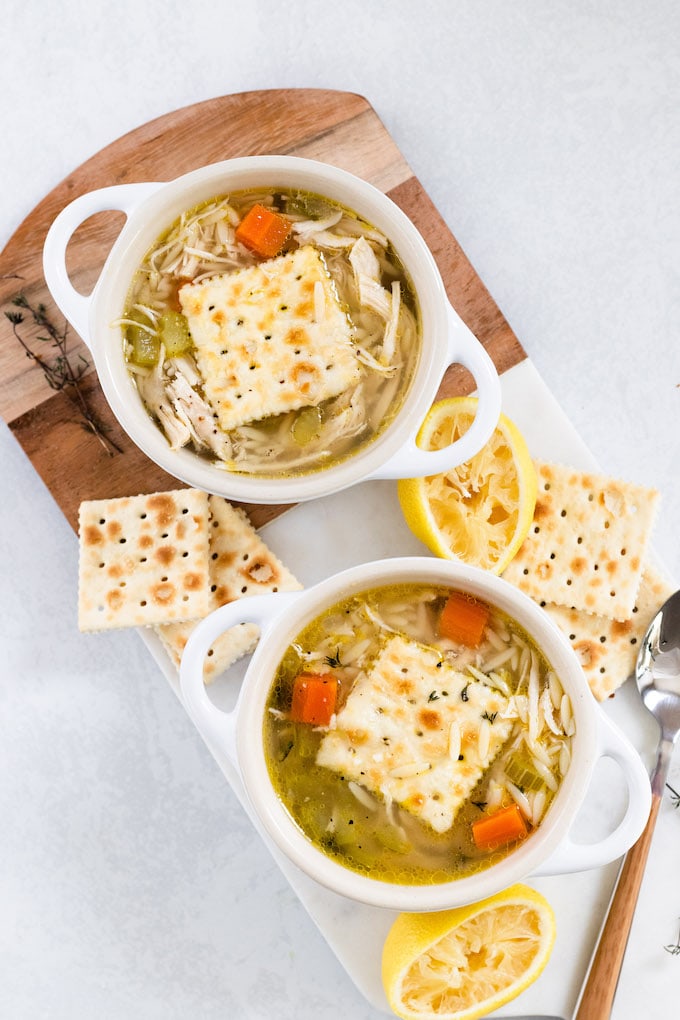 A bowl of soup with saltines and chicken and orzo soup. 