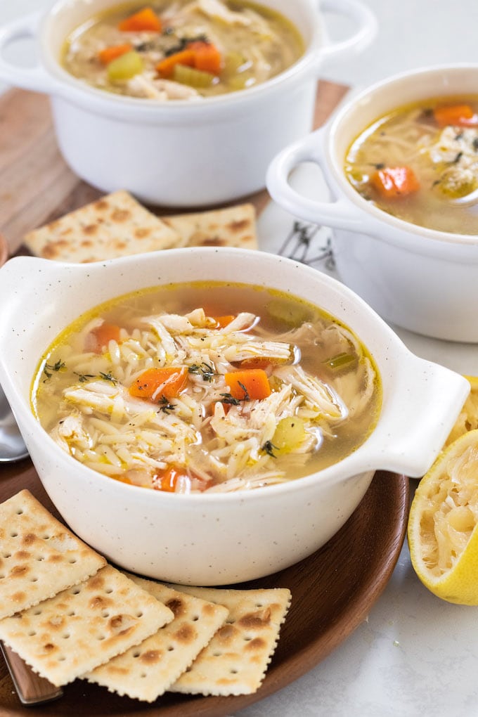 multiple bowls of soup with crackers and lemon. 