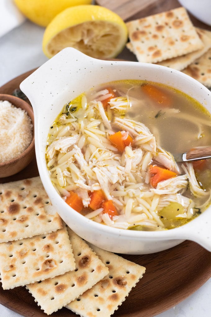 a bowl of soup with crackers and a spoon. 