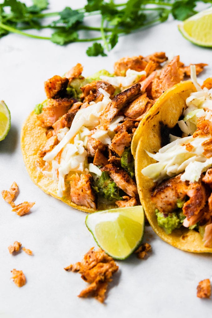 A taco filled with blackened salmon tacos with slaw and guacamole.