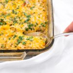 A spoon scooping chicken fajita casserole with quinoa out of the casserole dish