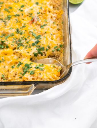 A spoon scooping chicken fajita casserole with quinoa out of the casserole dish