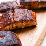 Blackened salmon filets on a wooden plank.