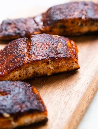 Blackened salmon filets on a wooden plank.