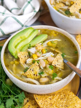 a bowl of soup with avocado on top.