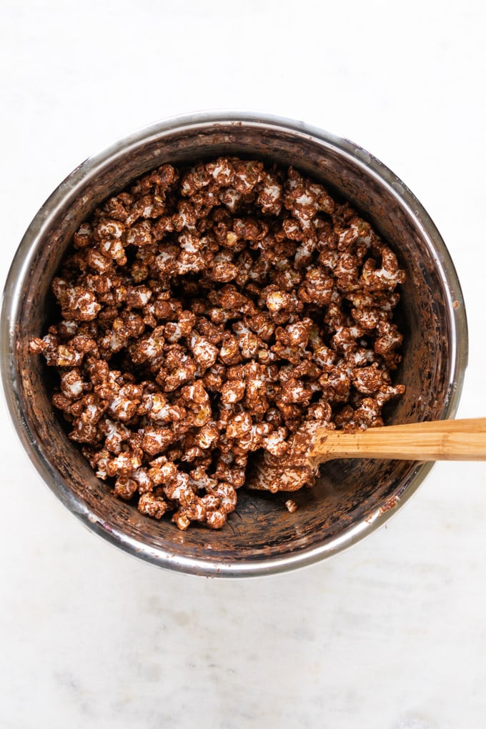 A bowl of chocolate peanut butter popcorn with a spatula. 