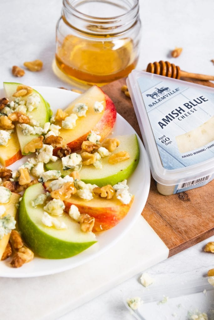 Apples on a plate with cheese crumbles and honey