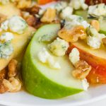 Apple slices on a plate with honey and walnuts