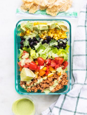 Taco salad meal prep bowls with dressing on top.