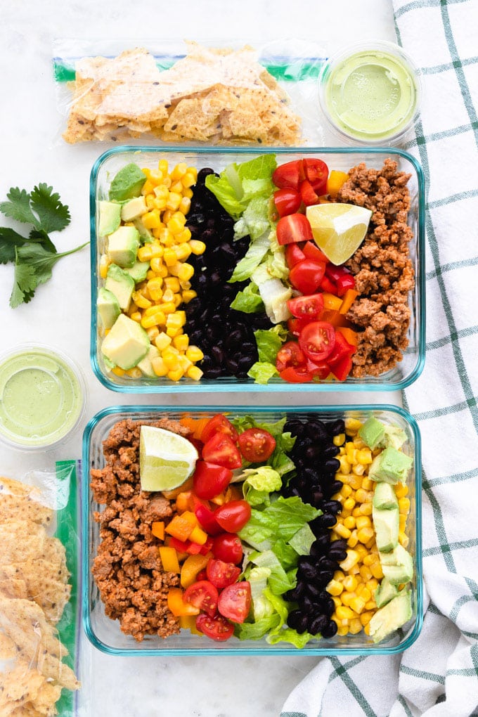 A healthy taco salad with toppings on the side.